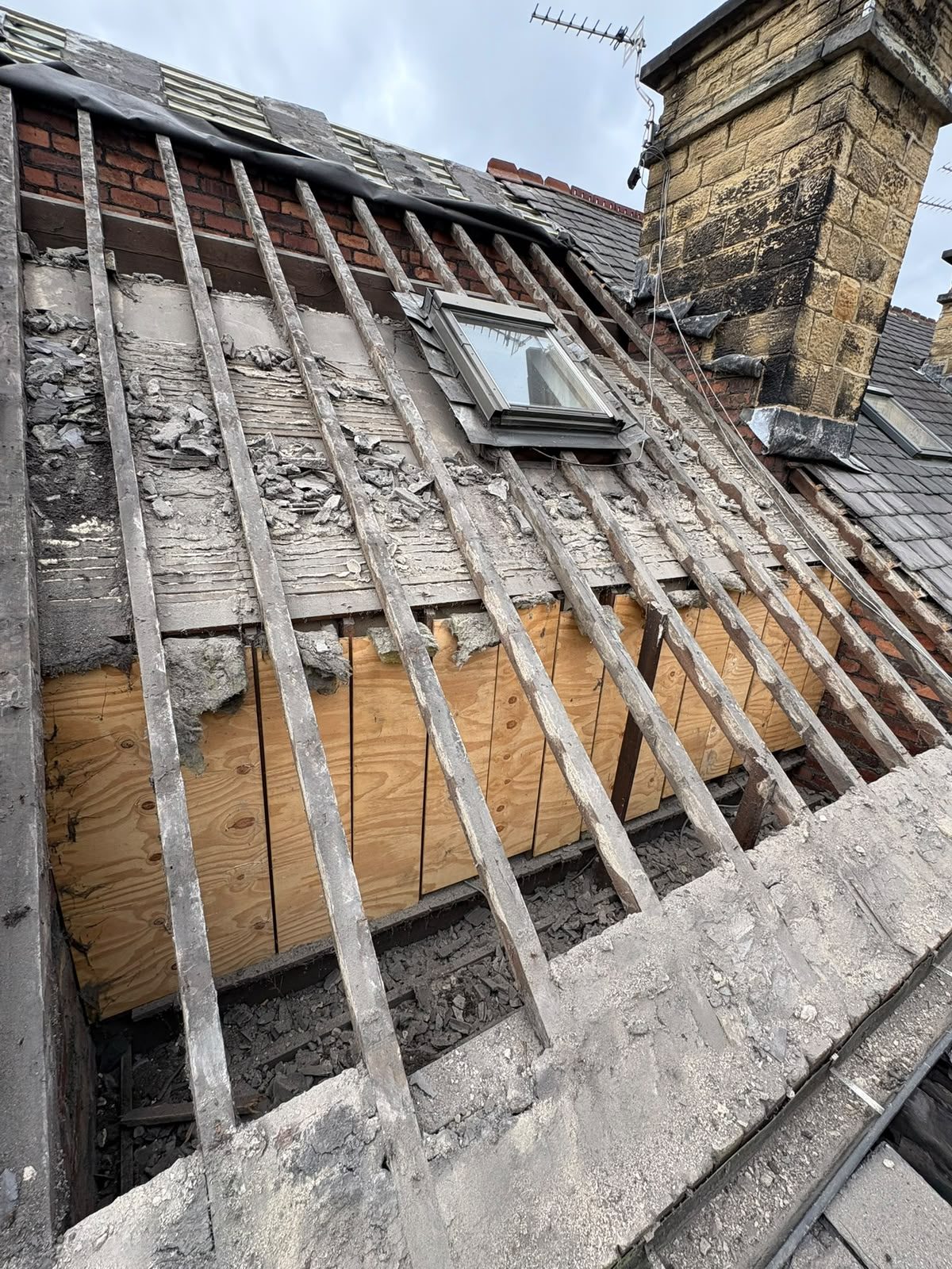 Roof stripped back to bare rafters and old battens, exposing perished underlay before re-covering