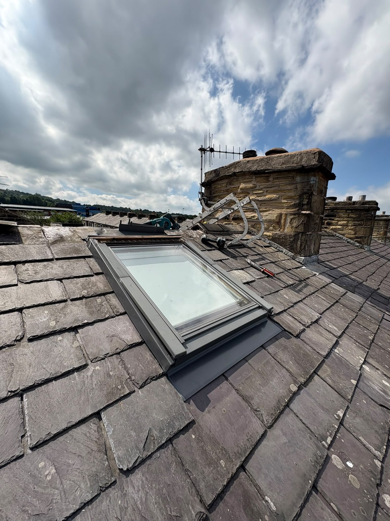 Roof window installed into a stone slate roof with lead flashing kit dressed around the frame